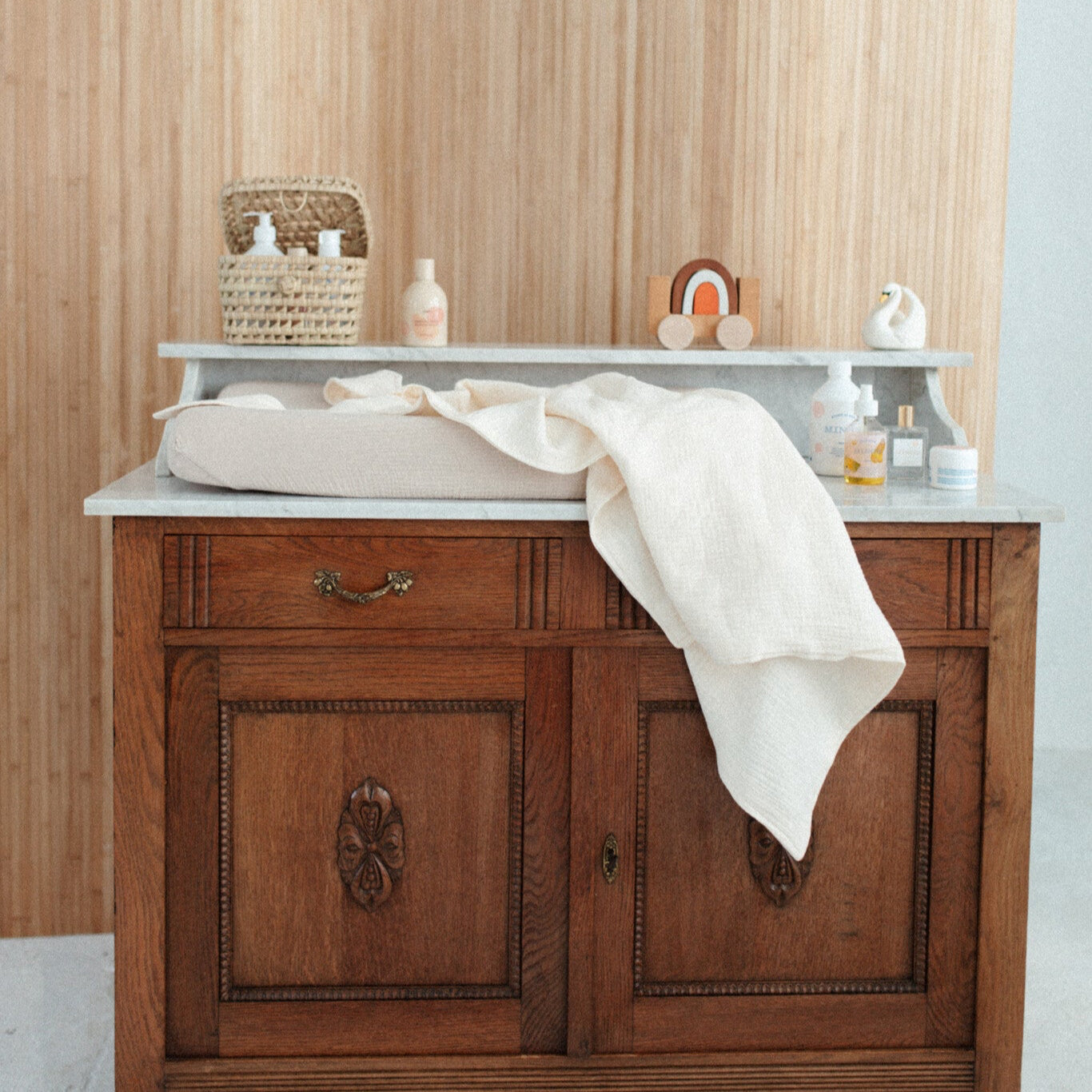 handdoek met capuchon liggend op een commode. met verzorgingsproducten.
