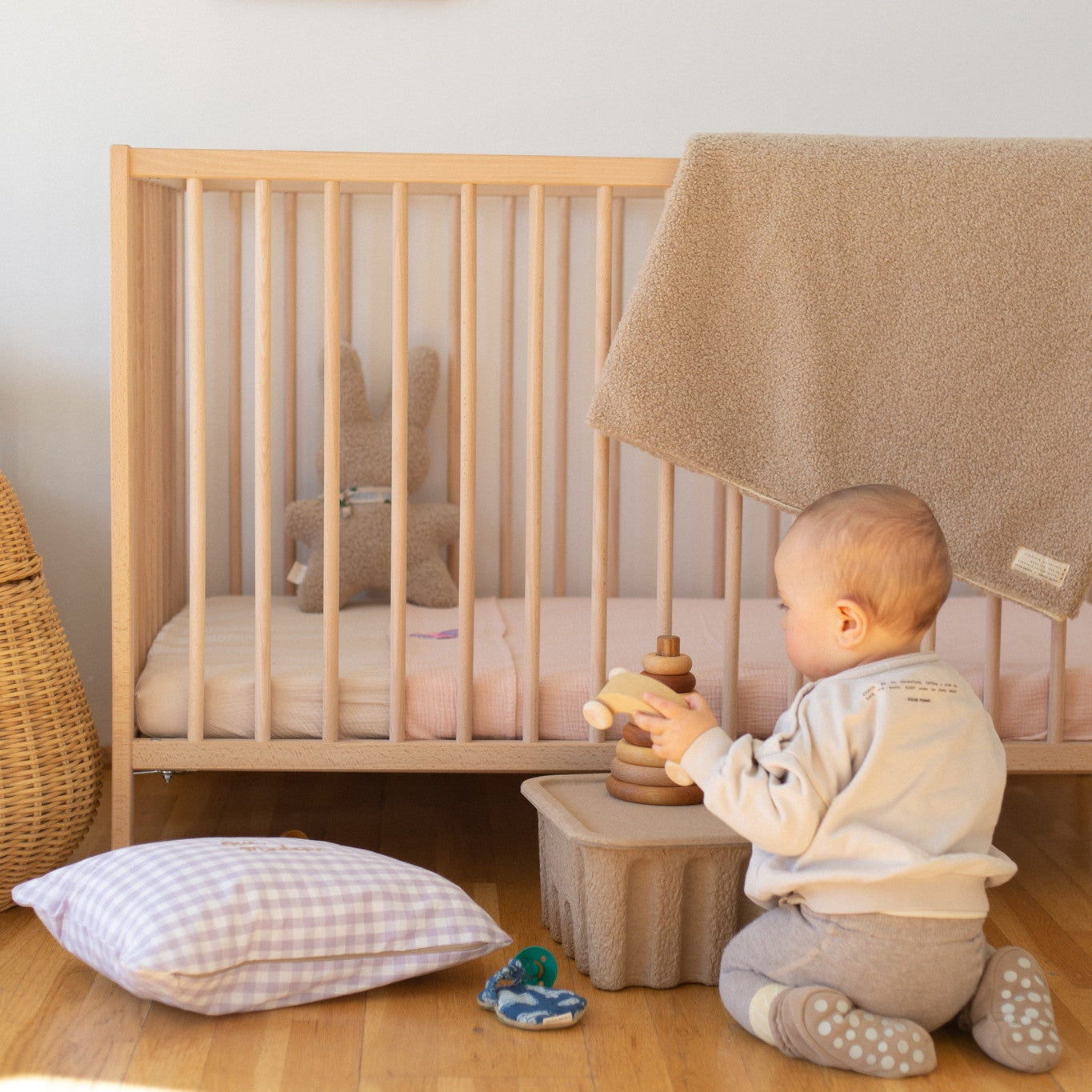 baby zit naast ledikant. gepersonaliseerde kussen, teddy knuffel, roze gepersonaliseerde laken.
