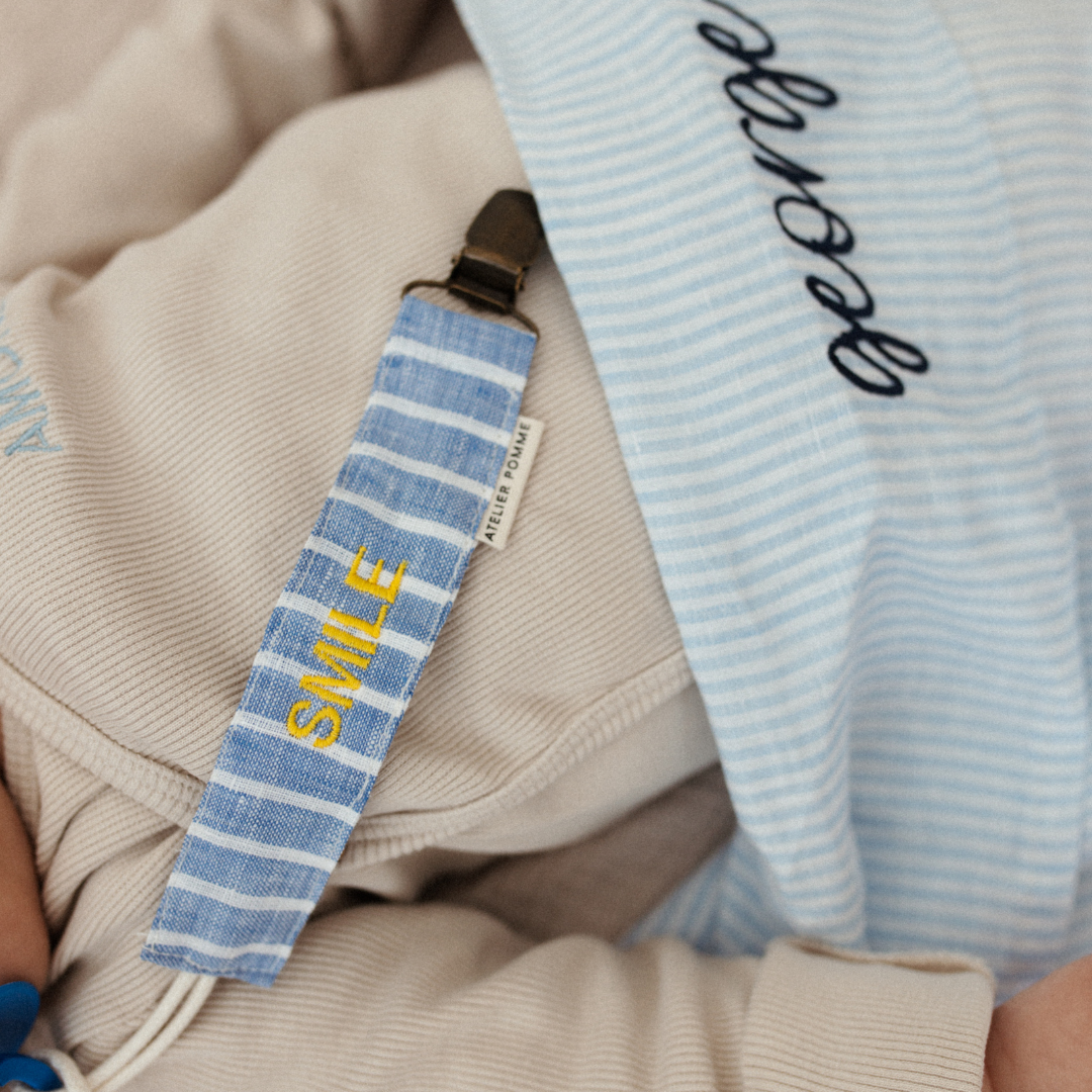 baby ligt onder laken met gepersonaliseerde tekst en speenkoord met tekst