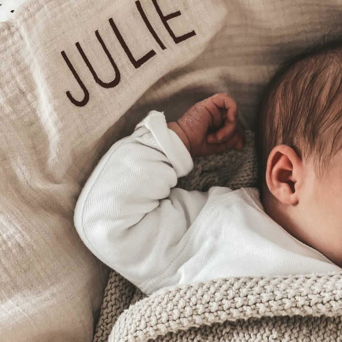 baby ligt in gebreide deken en laken met gepersonaliseerde tekst.
