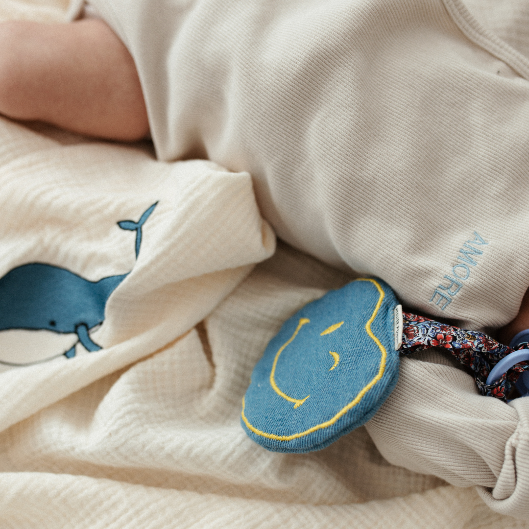 baby ligt op laken met icoon, speenknuffel.