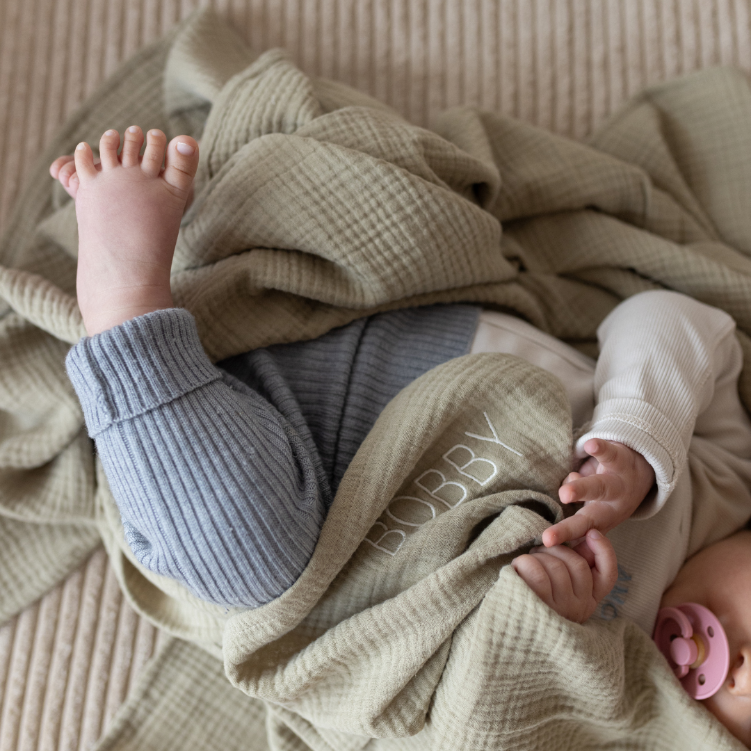 baby ligt in laken met tekst.