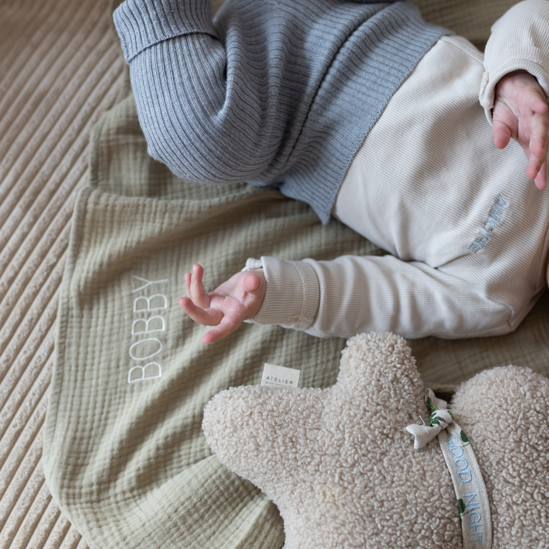 baby ligt op groene laken met gepersonaliseerde tekst.