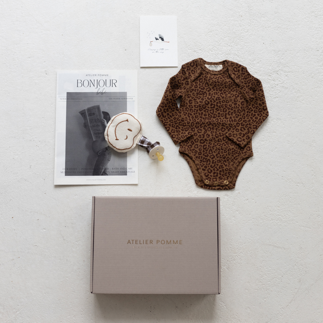 Cadeaubox met een gepersonaliseerde romper, speendoek en kaart