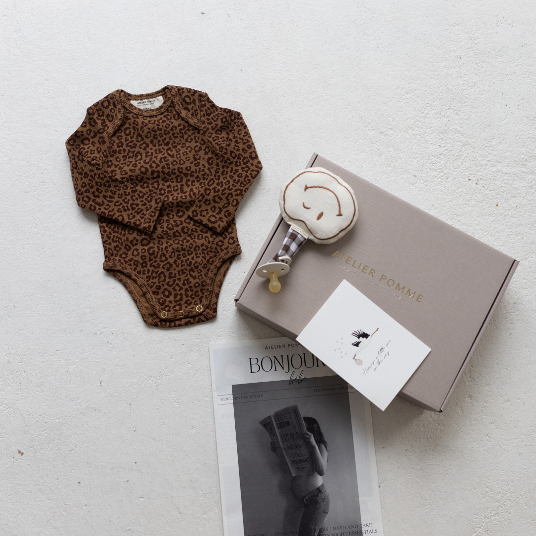 Cadeaubox met een gepersonaliseerde romper, speendoek en kaart