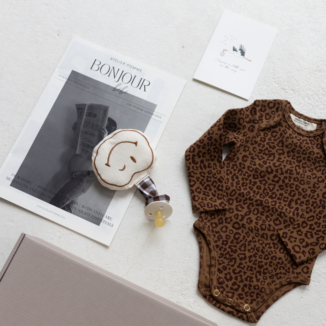 Cadeaubox met een gepersonaliseerde romper, speendoek en kaart