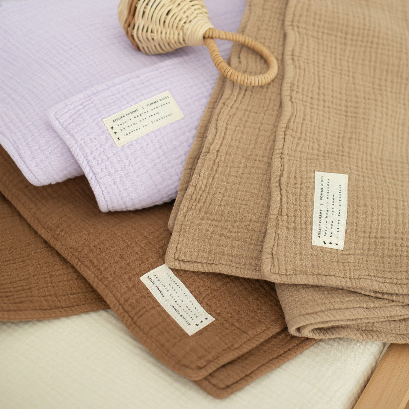 verschillende dekens van muslin materiaal in de kleuren: paars, bruin en groen