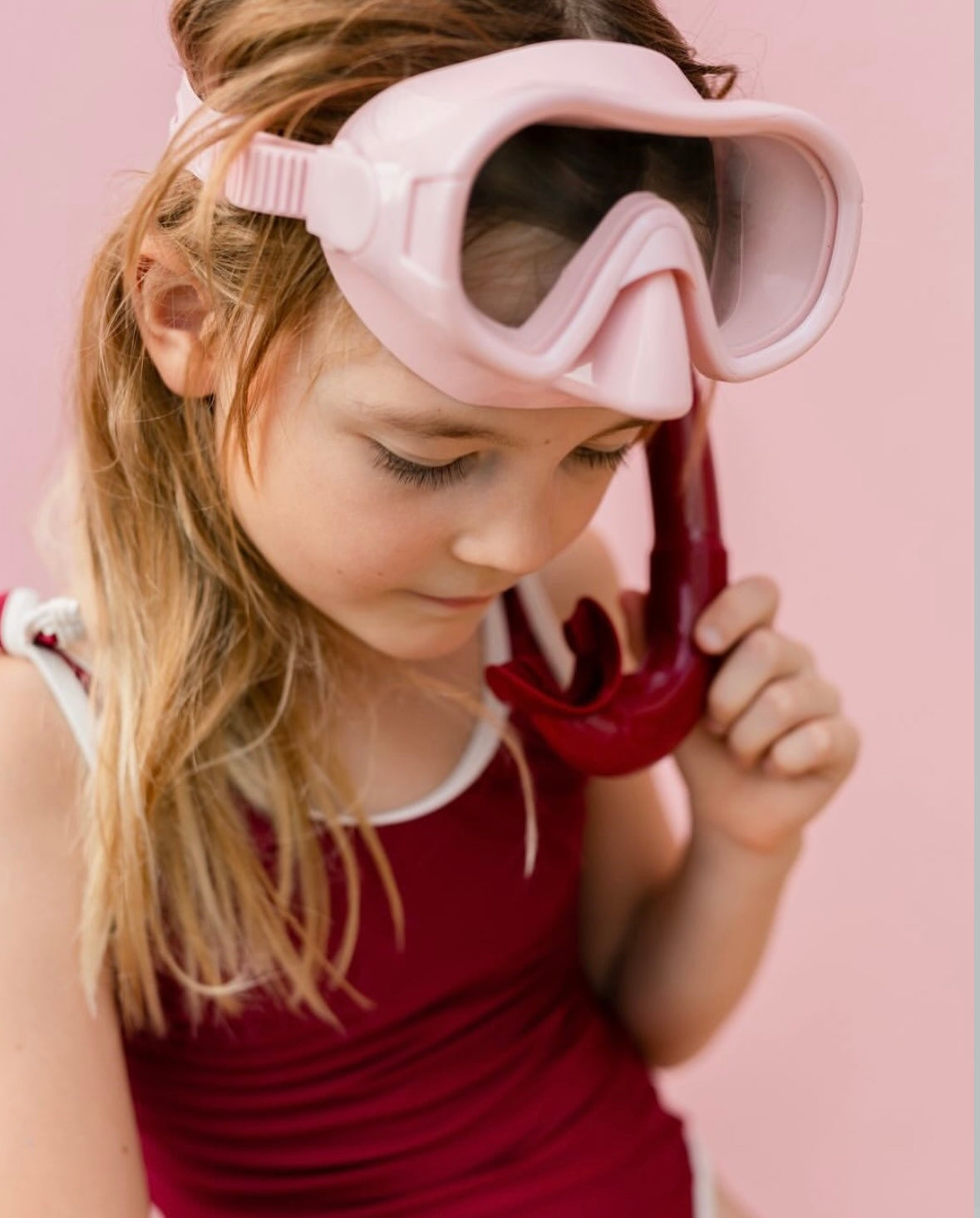 Een snorkelset met een roze duikbril en een rode snorkel