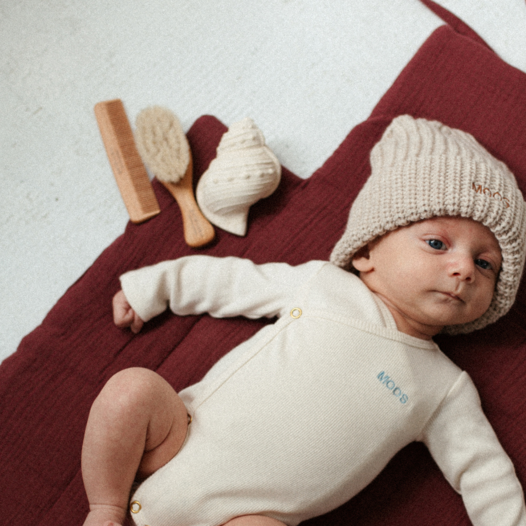 baby ligt op verschoonmat met bijtring, kam en borstel.