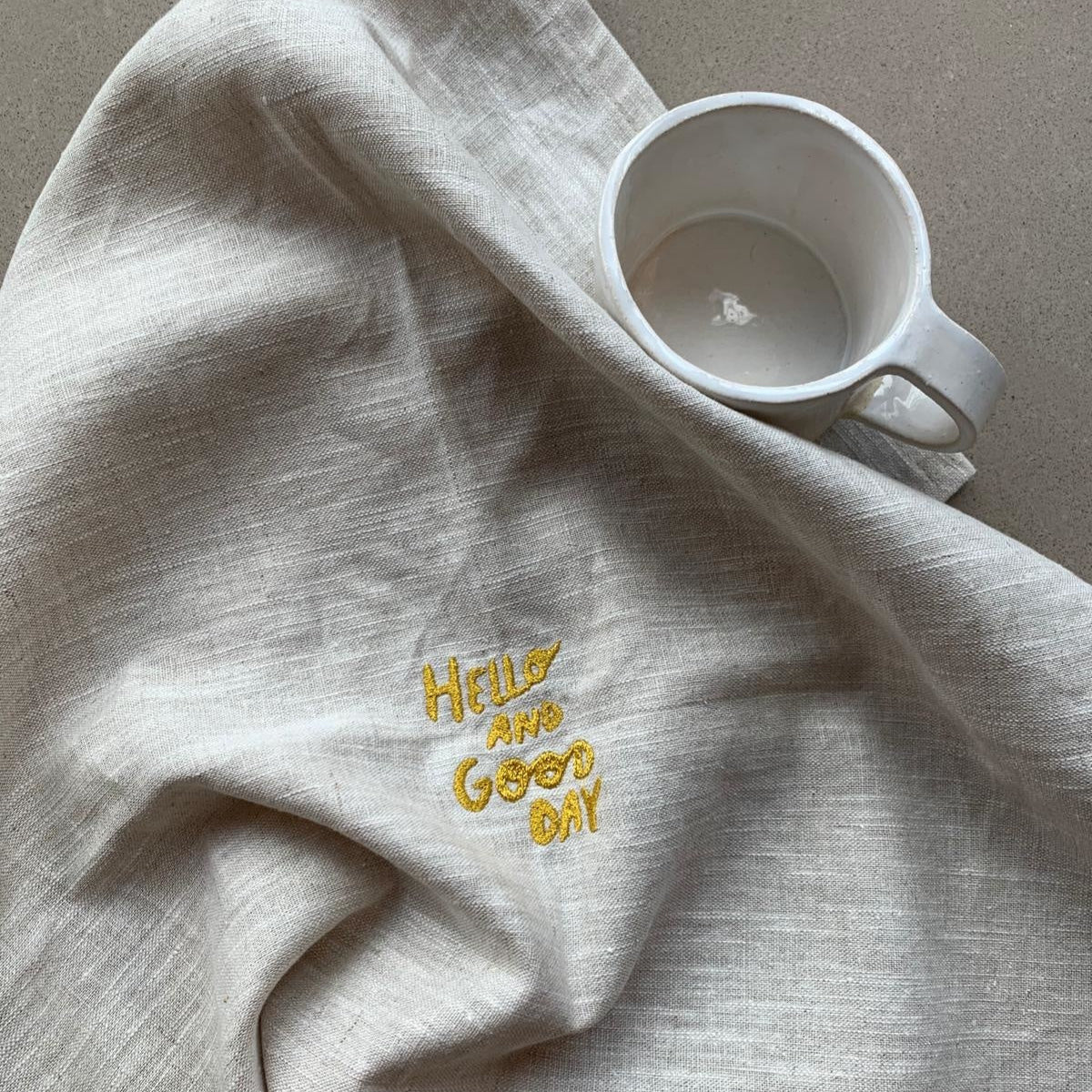 Beige theedoek, gemaakt van 100% linnen en gepersonaliseerd met een gouden quote. Het perfecte cadeau.