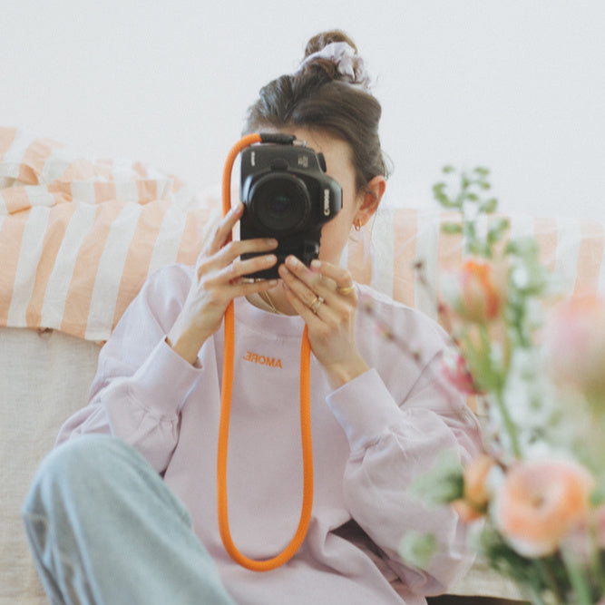 Vrouw in oversized lila trui met personalisatie van quote in oranje. Leuk voor op een spijkerbroek.