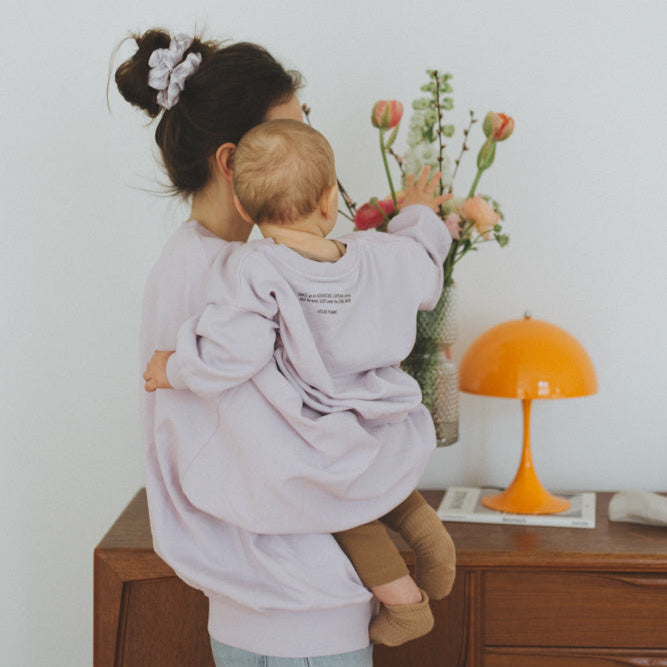 Vrouw en kind of baby in oversized lila trui met personalisatie van naam of icoon.