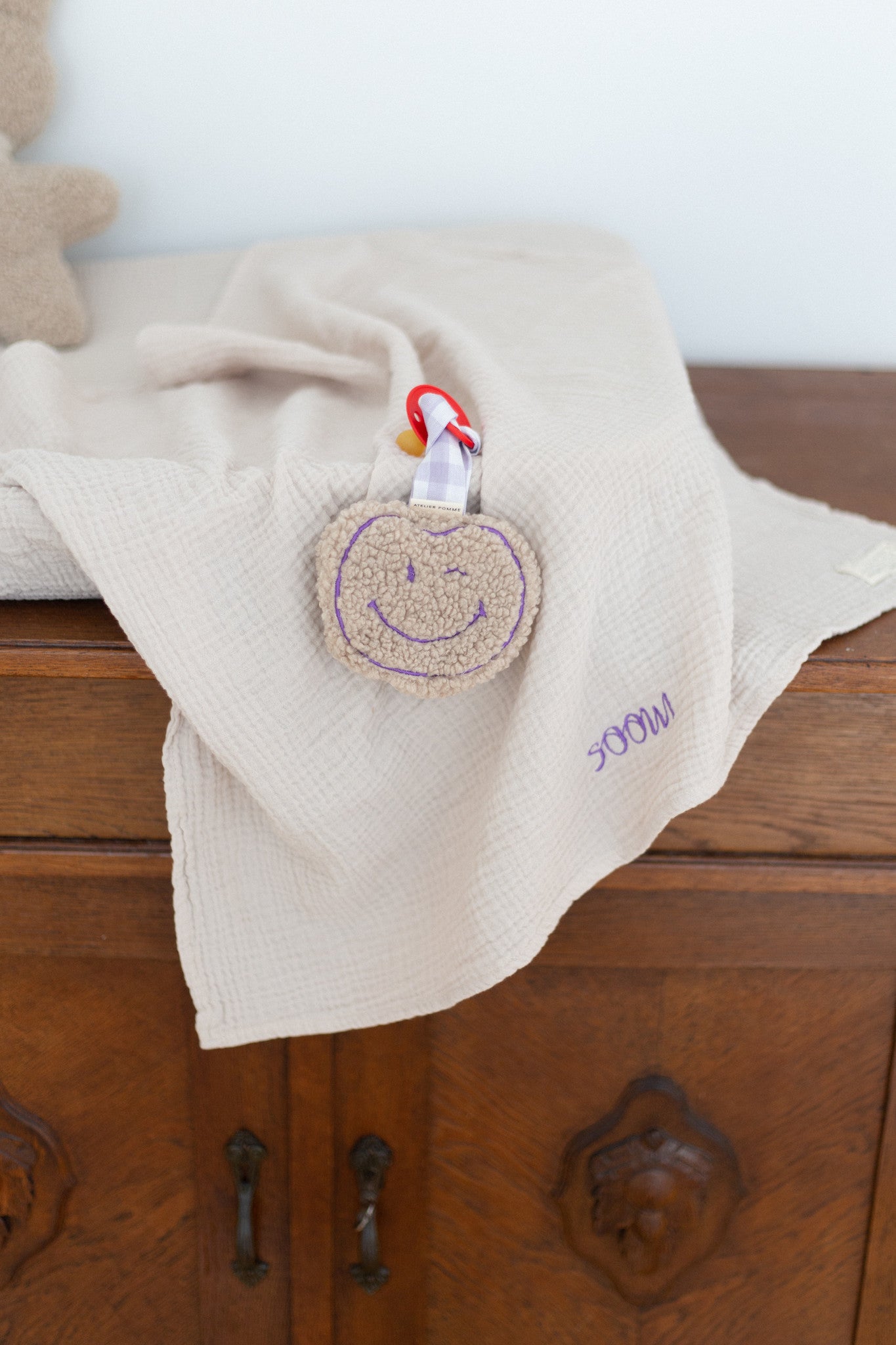 teddy knuffel met glimlach aan een geruit speenkoord