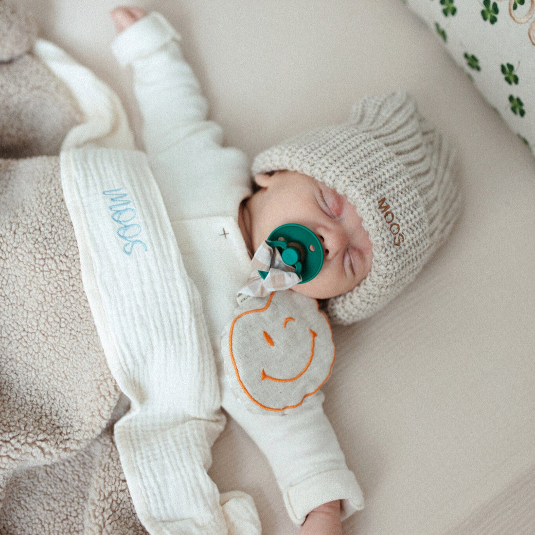 baby ligt onder laken met gepersonaliseerde tekst en teddy deken. 
