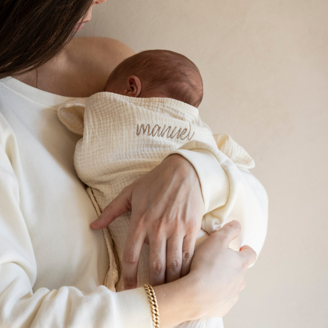 baby ingebakerd in laken met tekst en vastgehouden door moeder. 
