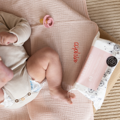 baby ligt op laken met babydoekjes en speen 