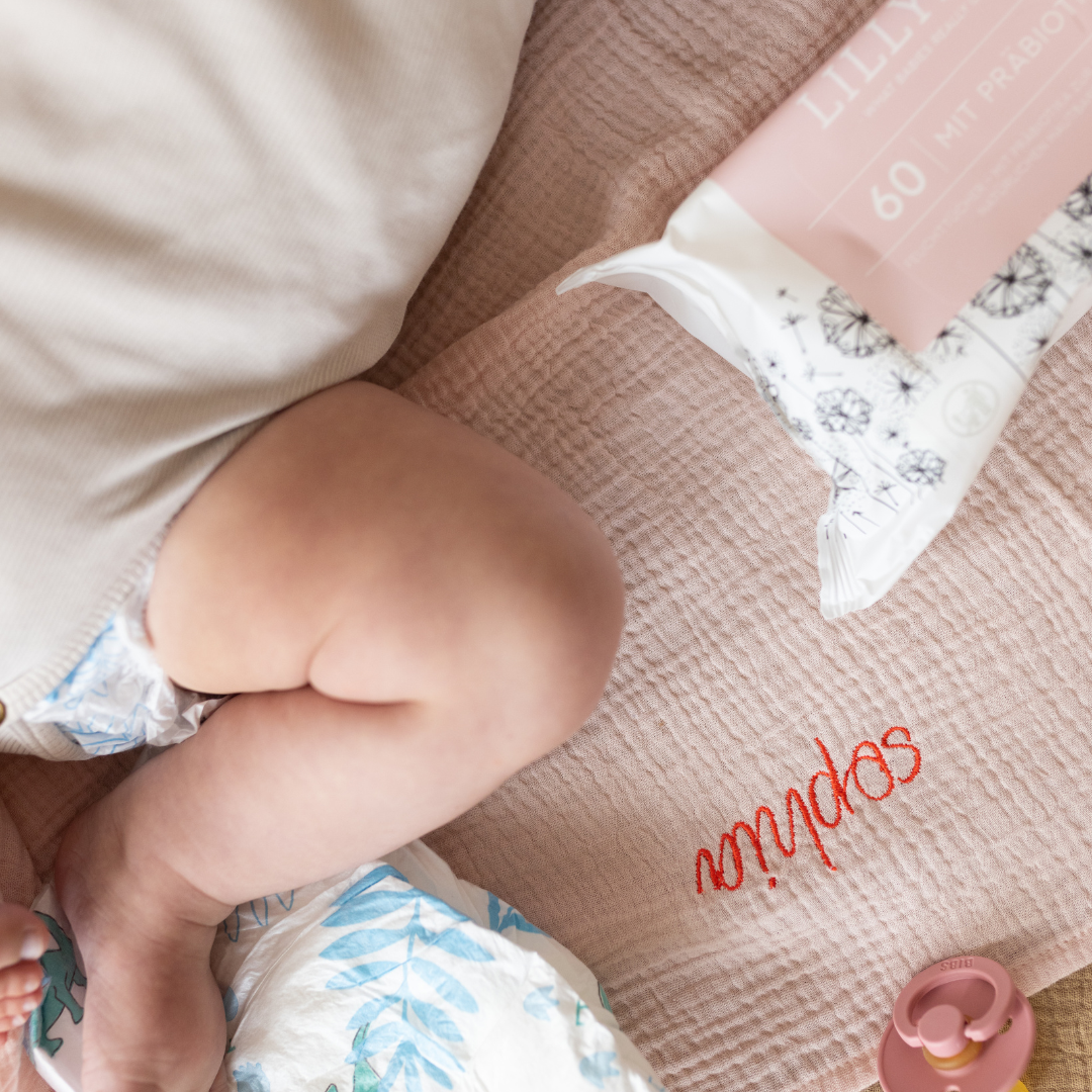 baby ligt op gepersonaliseerde laken met speen en babydoekjes 