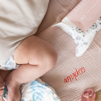 baby ligt op gepersonaliseerde laken met speen en babydoekjes 