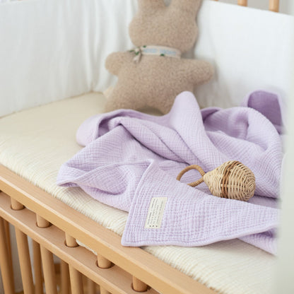 muslin doek in de kleur lila in bed van baby 
