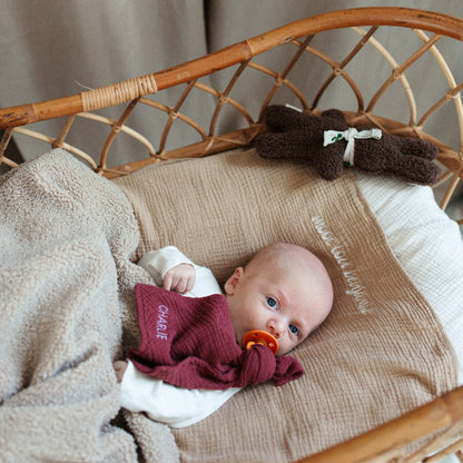 baby in bedje met speendoek in het bordeaux rood