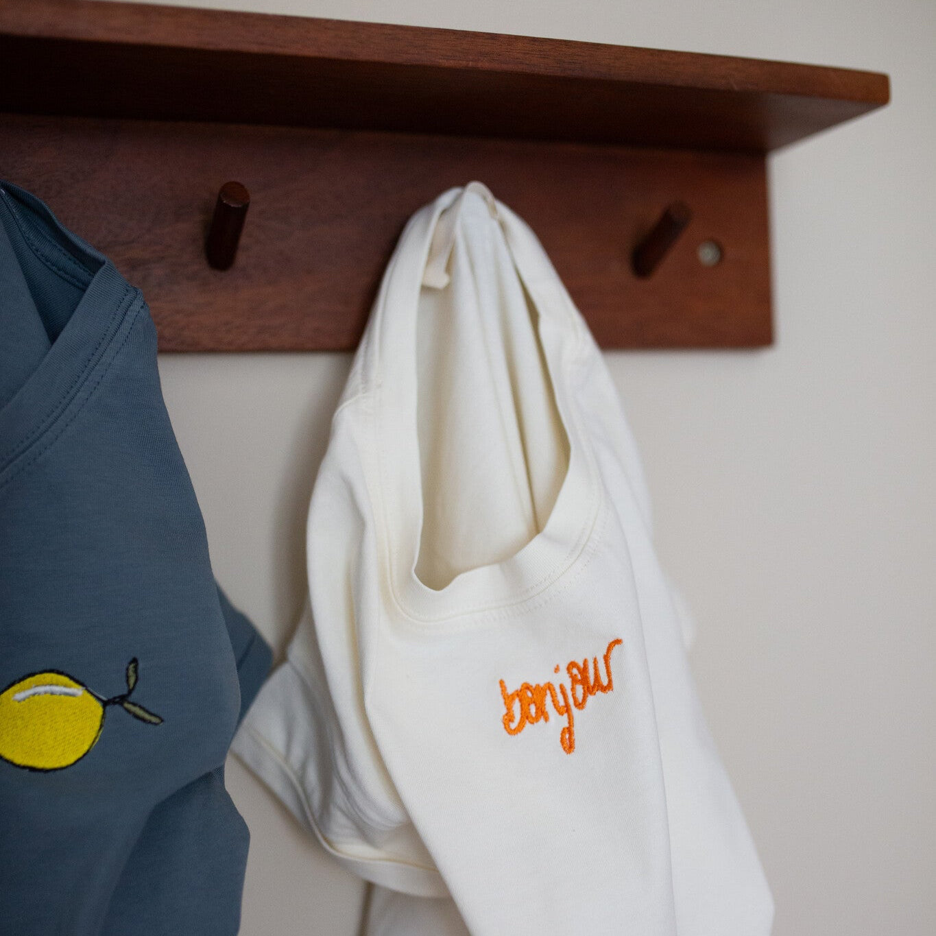 blauw en wit t-shirt met tekst en icoon hangen aan kapstok. 