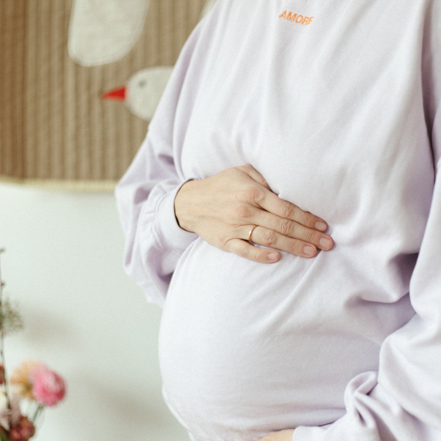 Zwangere vrouw in oversized lila trui met oranje personalisatie letters. 