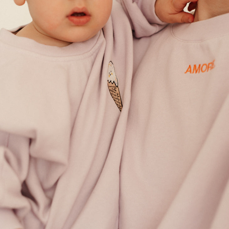 Vrouw en kind of baby in oversized lila trui met personalisatie van naam of icoon. 